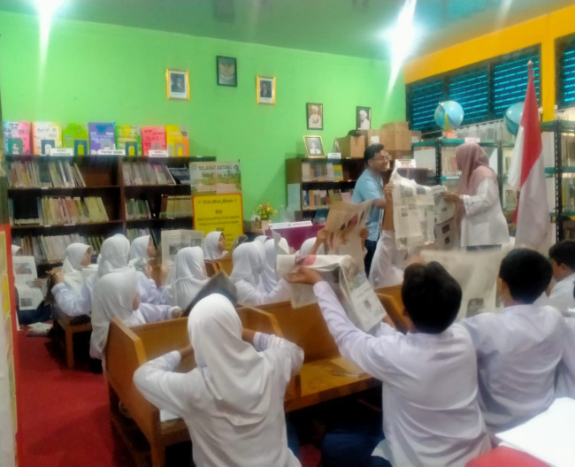 Kegiatan siswa belajar di perpustakaan dengan materi menggunakan sarana koleksi Koran 